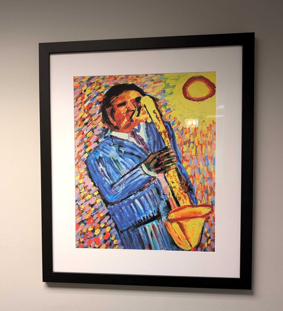 A framed painting of a person playing a saxophone, characterized by bold colors and dynamic brushstrokes.