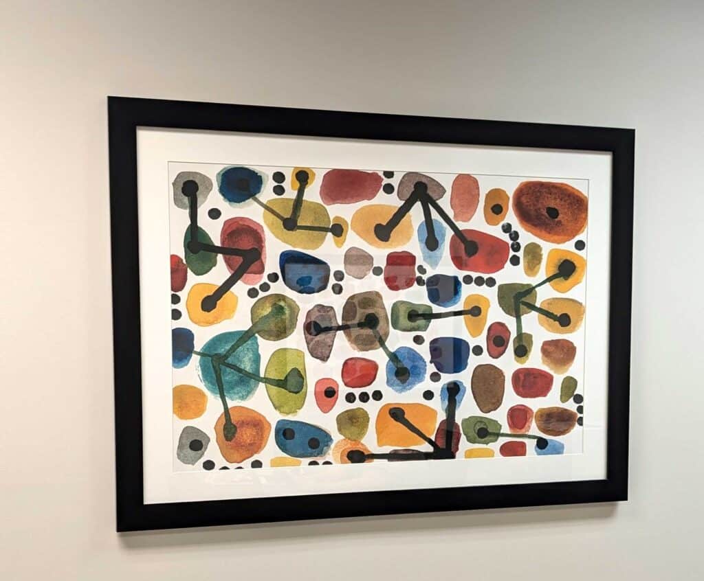 Framed abstract painting with colorful blobs and black lines.