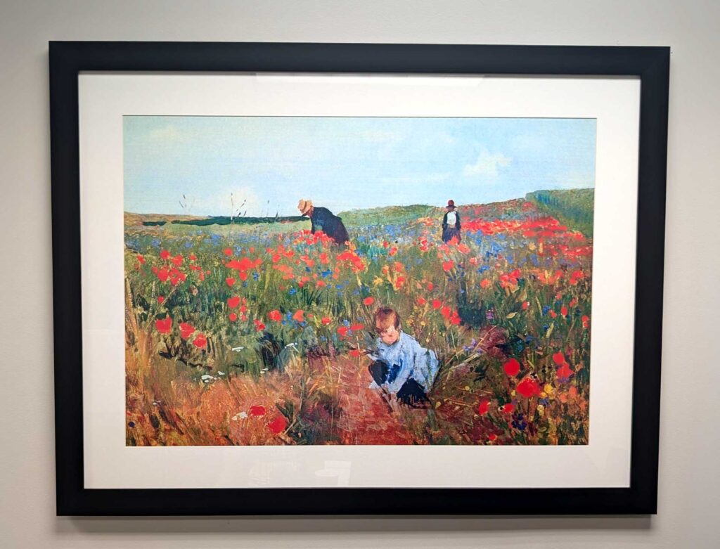 Framed painting of a field with red poppies, featuring three people, including a crouching child in the foreground.