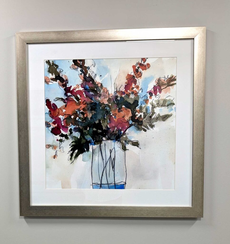 A framed abstract watercolor painting of a vibrant flower bouquet in a vase.