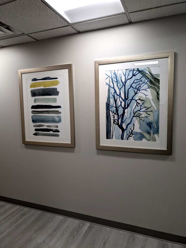 Two framed abstract artworks hanging on a light gray wall.