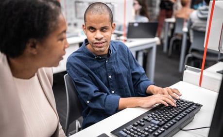 woman and blind man sitting at a computer